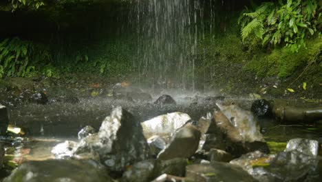 Sonnenbeschienene-Felsen-Betonen-Die-Schönheit,-Während-Das-Wasser-Anmutig-Einen-Bezaubernden-Wasserfall-Hinabstürzt