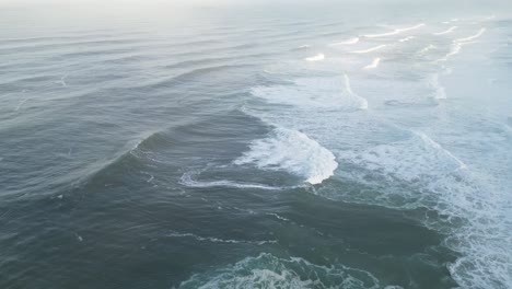 aerial shot of waves crashing on the coast near farol, nazaré, portugal