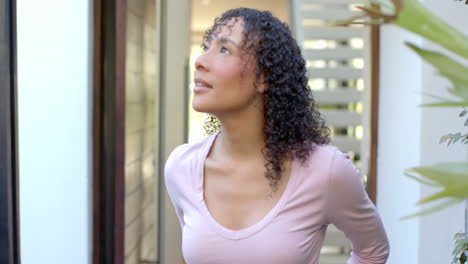 smiling woman with curly hair standing and looking up in modern home