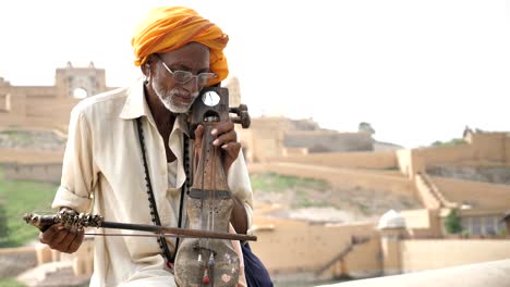 un anciano tradicional con un pagri jugando al sarangi
