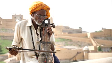 an old traditional man wearing pagri playing sarangi