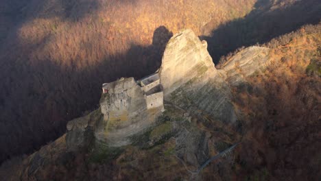 majestic ancient fortress perched on a steep cliff during autumn, aerial view