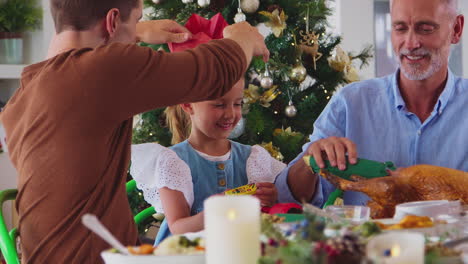 familia de varias generaciones celebrando navidad en casa con sombreros de papel de galletas antes de la comida