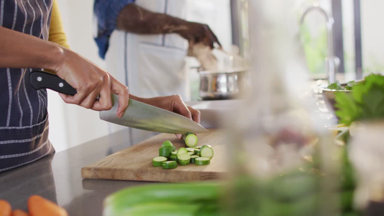 Video of hands of african american couple preparing meal together in kitchen