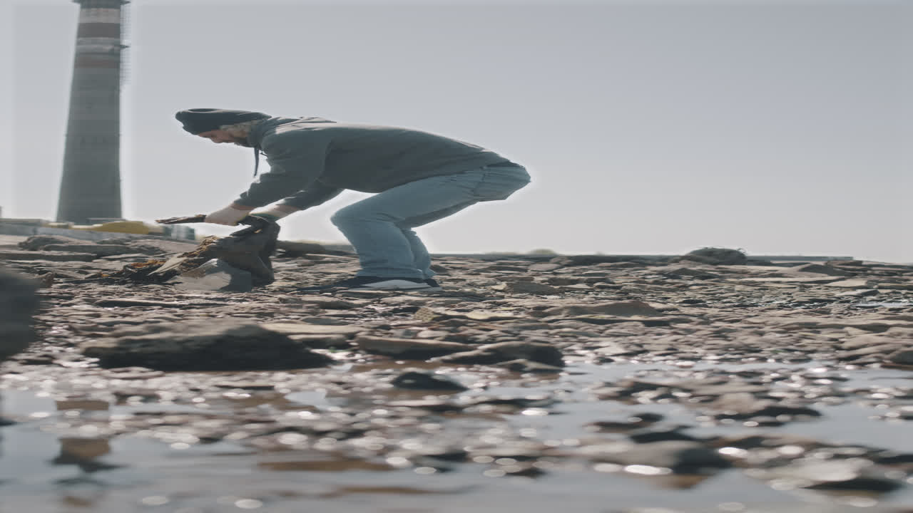 Environmental Activist Picking Litter on Cobble Shore