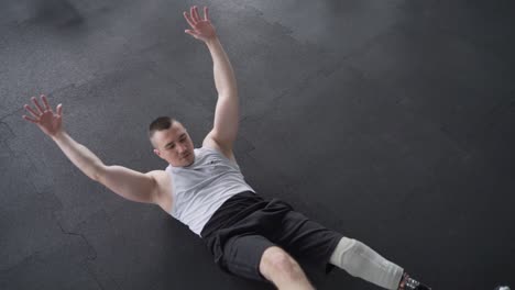 atleta con pierna protésica haciendo ejercicios abdominales en el piso del gimnasio