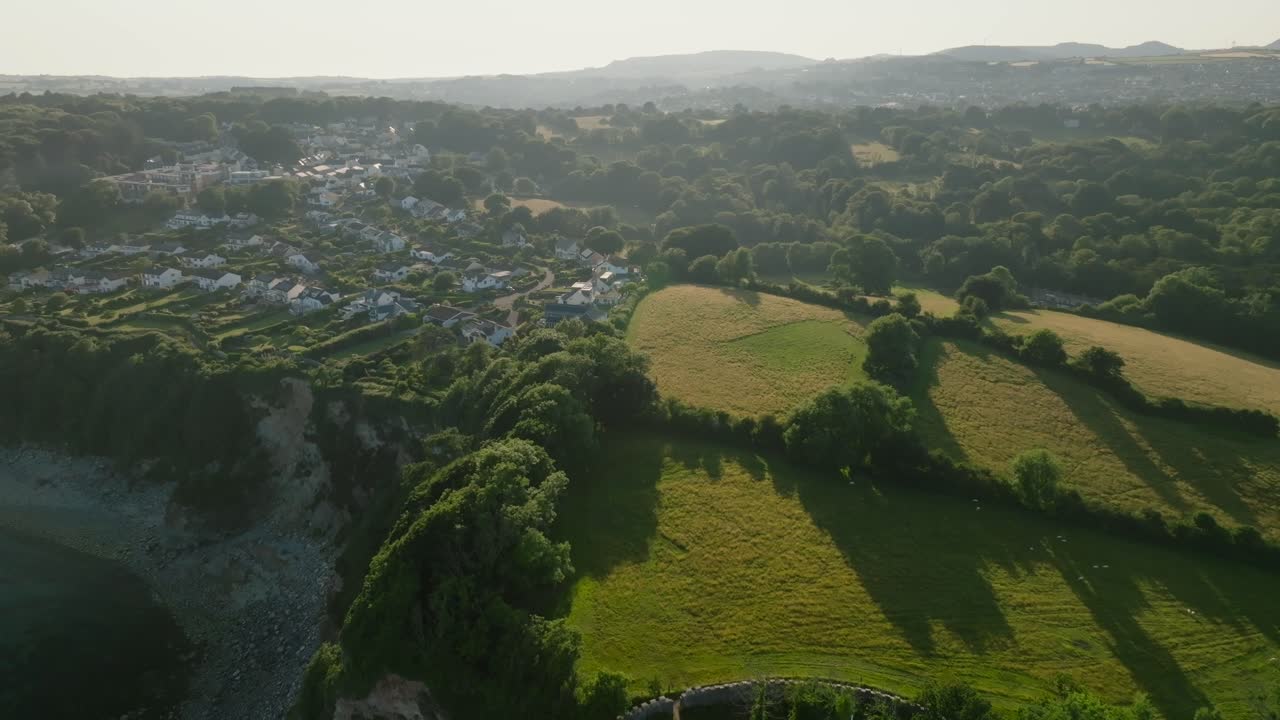 Village nestled next to sea cliffs in green countryside. Charlestown, Cornwall, UK.