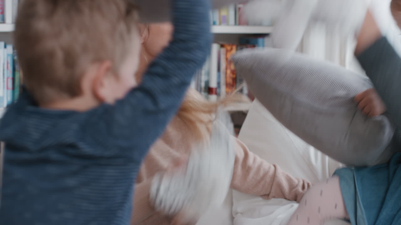 happy family having pillow fight mother and father enjoying playing with children at home having fun together on weekend 4k footage