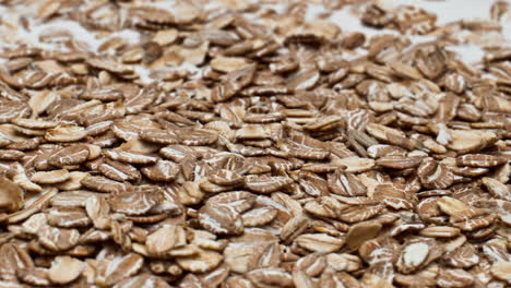 raw oat flakes dropped into natural yogurt for healthy breakfast close up.