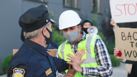 policjant pcha budowniczego w proteście przeciwko covidowi 19 na ulicy