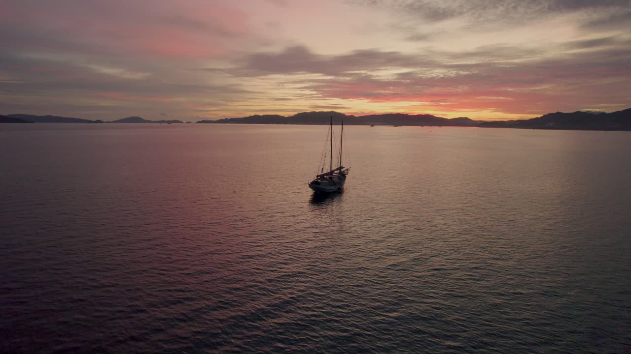 silueta de un solo barco y montañas al atardecer, costa de malasia