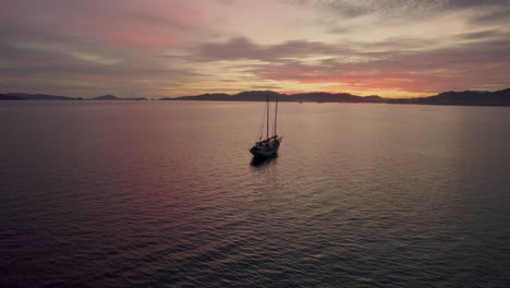 silueta de un solo barco y montañas al atardecer, costa de malasia