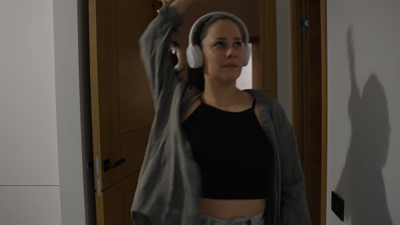 Woman dancing indoors with headphones