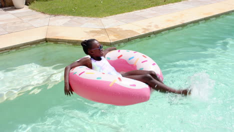 relaxing in pool, child floating on pink inflatable ring under sunny sky