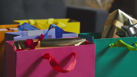 Close-Up-Of-Gift-Wrapped-Presents-In-Colourful-Bags-With-Tag-On-Table-In-Lounge-At-Home-1