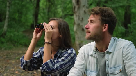 couple using binoculars in the forest