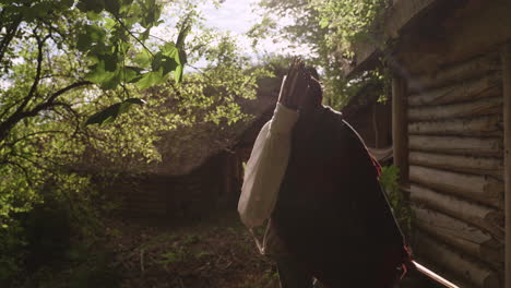 person carrying sticks in a wooden hut setting