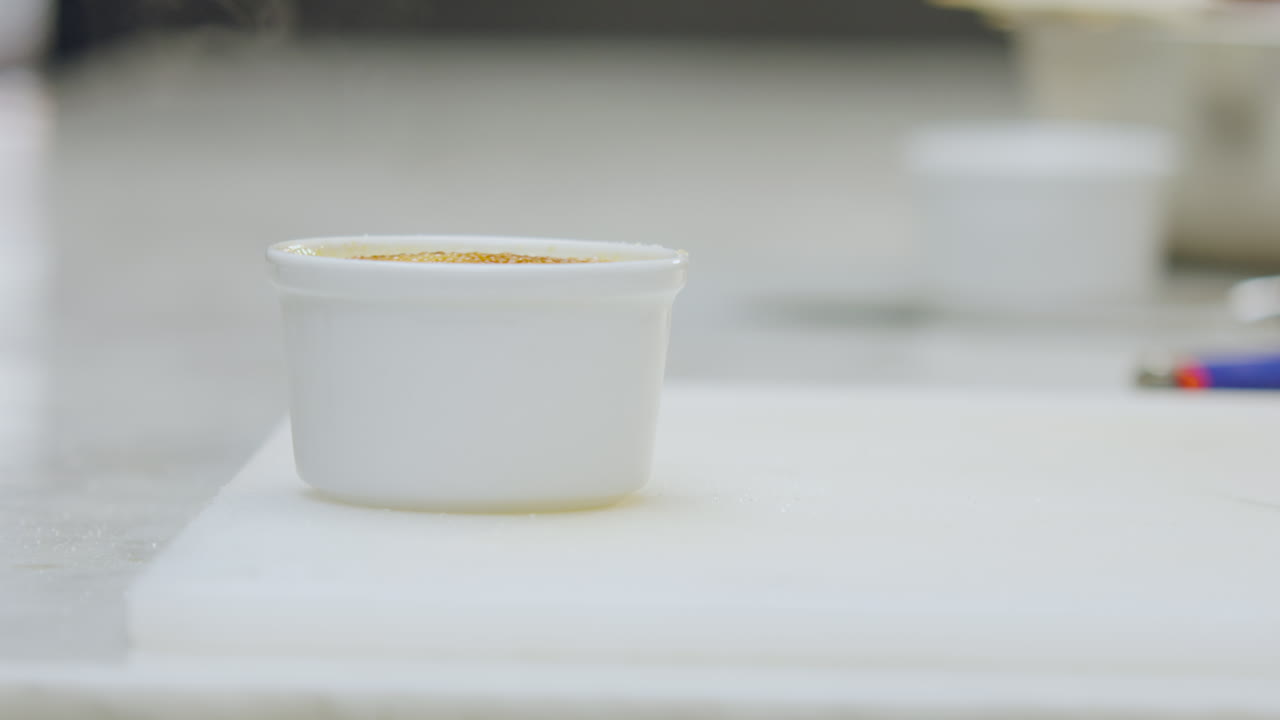 Close-up of a freshly flamed creme brulee dessert, still releasing smoke over the caramelized surface