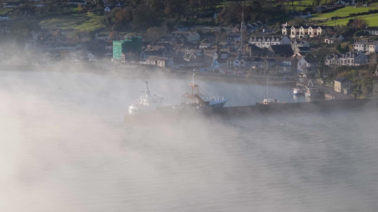 Carlingford town and marina on a misty morning with boats and distant houses in County Louth