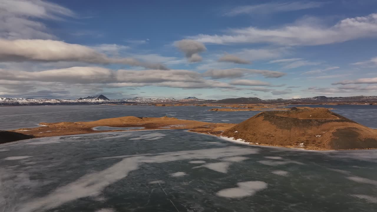 Frozen expanse of Lake Mývatn near Skútustaðir with volcanic hills and distant snowy peaks. Reykjahlíð, Iceland