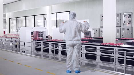 worker in protective suit observing meat processing line