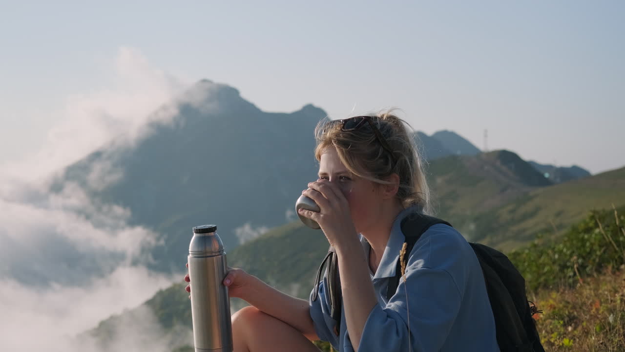 mujer disfrutando de una bebida en la cima de una montaña