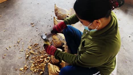woman is sculpturing the design on wood with hammer in 4k