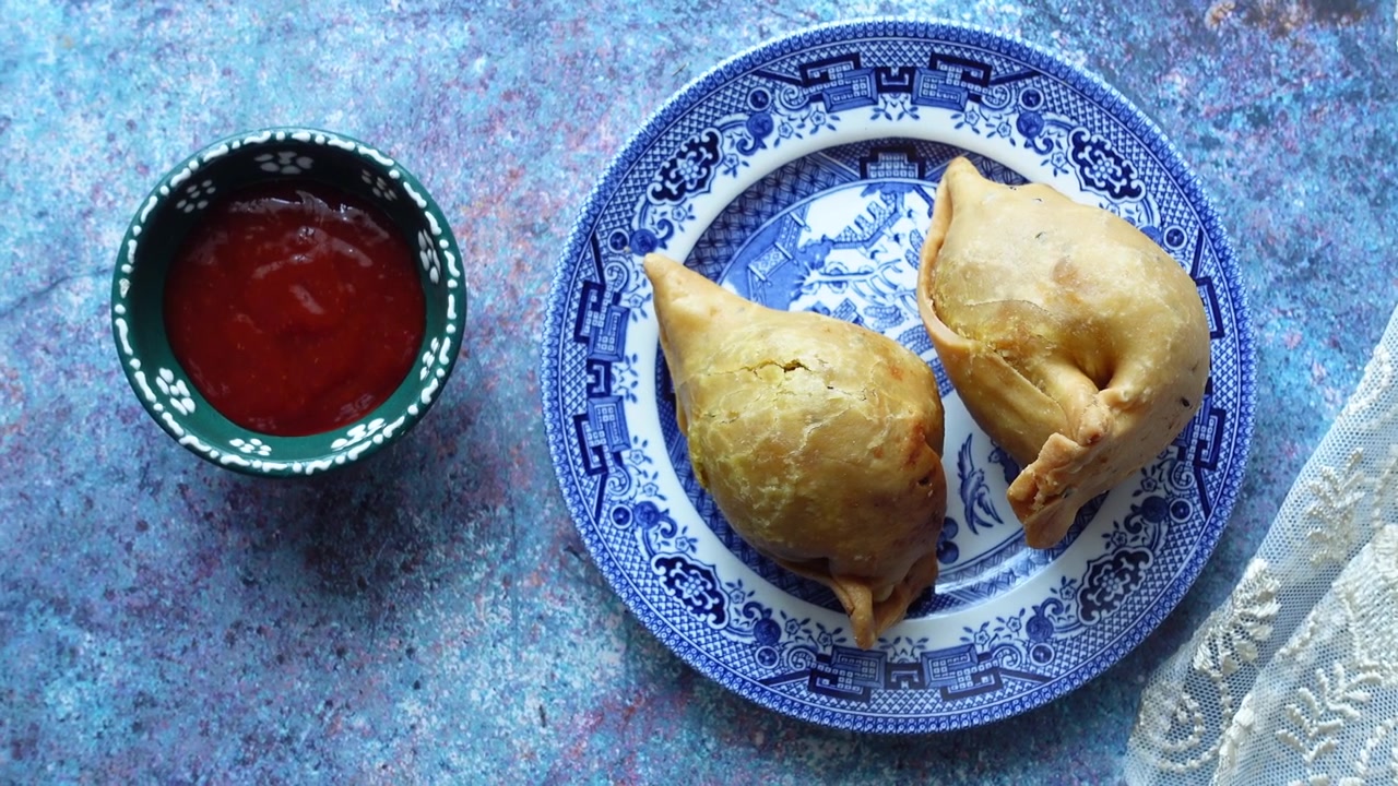 Due samosa croccanti serviti su un piatto a fantasia blu