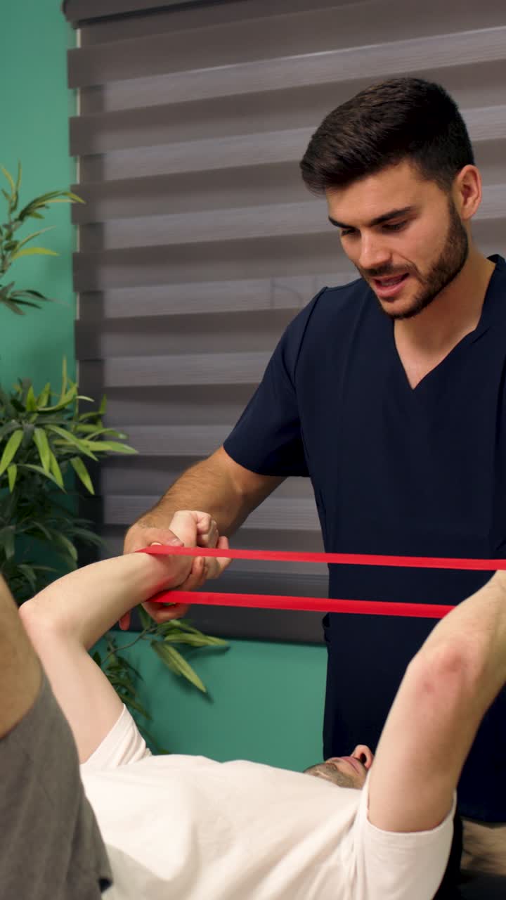Fisioterapeuta auxiliando paciente masculino com exercícios de braço usando faixa de resistência
