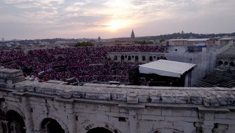 Drohne-Bewegt-Sich-Vorwärts-Und-Hoch-über-Der-Arena-Von-Nîmes-Bei-Sonnenuntergang-Warten-Die-Leute-Auf-Das-Stromae-konzert