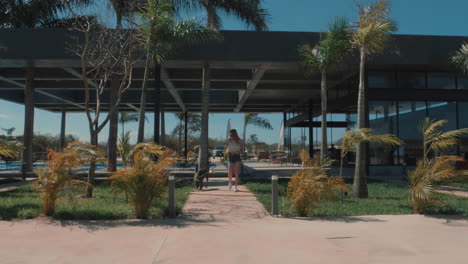 young woman walking her dog at a pet friendly resort, slow motion