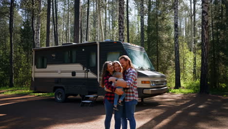 a happy family embracing in front of their rv in a forest