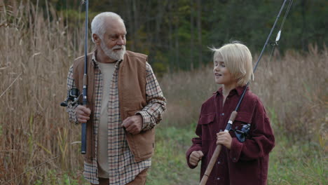 grandfather and grandson walking with fishing rods
