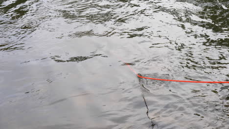 Cuerda-Roja-Con-Un-Imán-Pescando-En-Aguas-Onduladas-Un-Objeto-Valioso