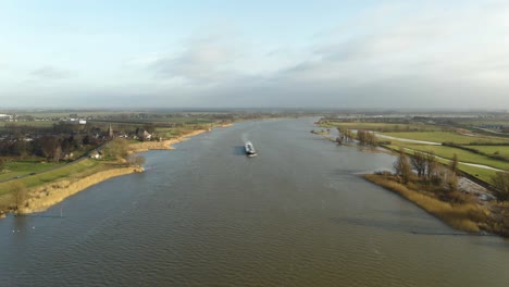 Vista-Aérea-Escénica-De-Drones-De-Un-Gran-Barco-Navegando-Por-El-Río-Lek-En-La-Ciudad-Holandesa-De-Ameide