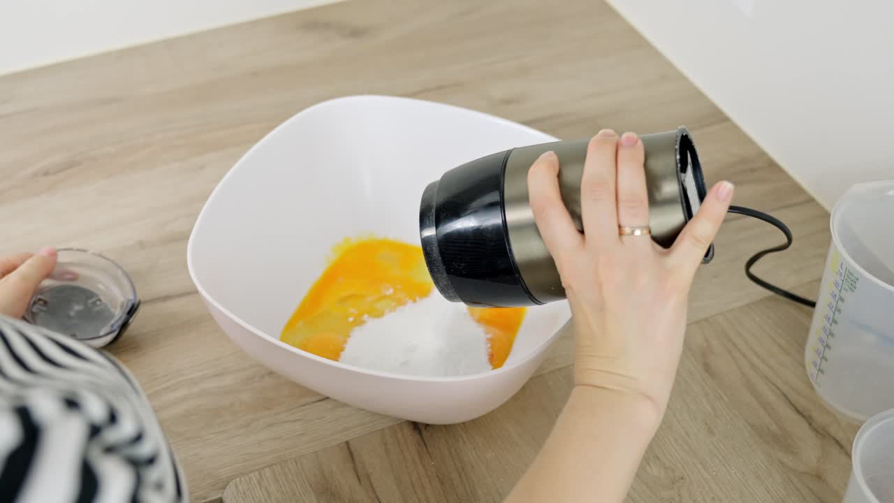 Close-up of powdered sugar being combined with egg yolk during tiramisu making process.