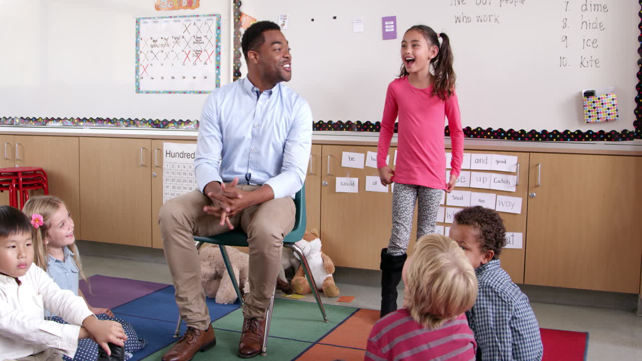 Hispanic schoolgirl standing with teacher in front of class