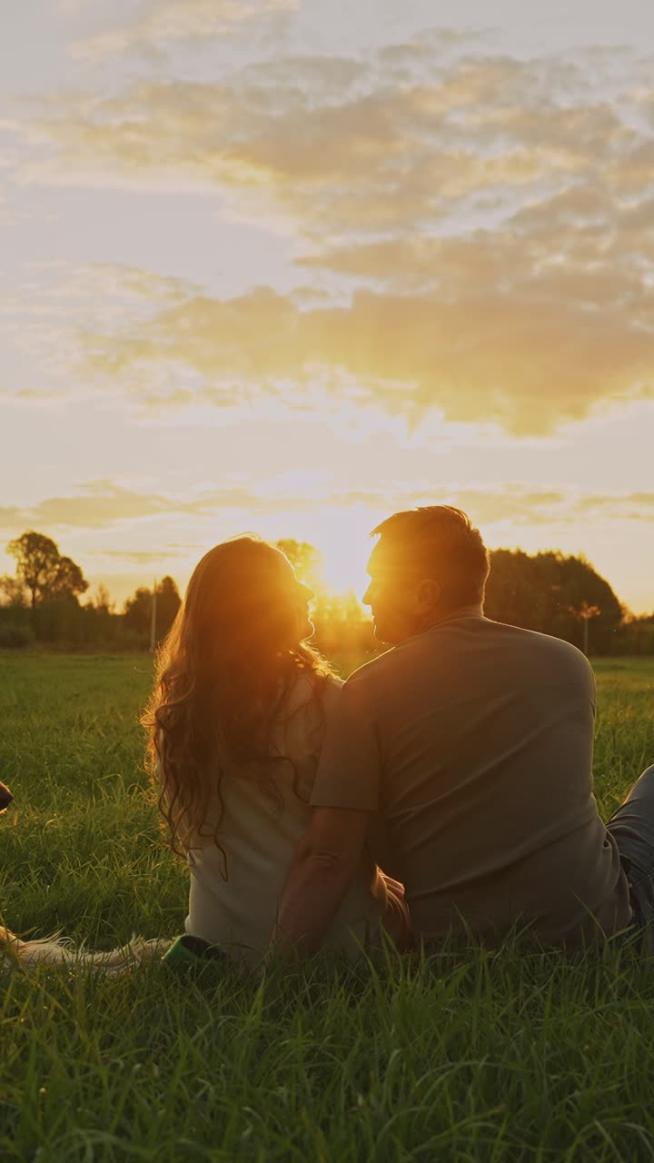 Couple Sitting in a Meadow at Sunset