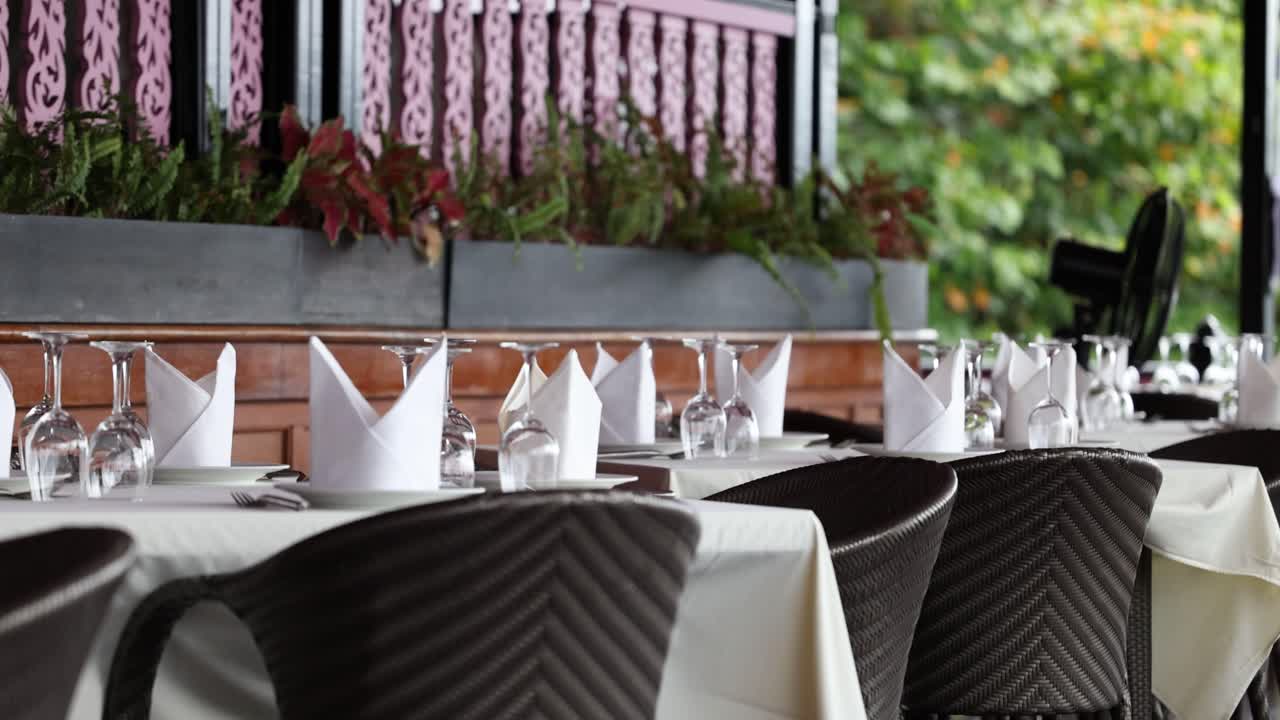 A serene restaurant scene in Phuket, Thailand, showcasing elegantly set tables with lush greenery and soft natural lighting