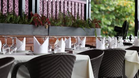 a serene restaurant scene in phuket, thailand, showcasing elegantly set tables with lush greenery and soft natural lighting