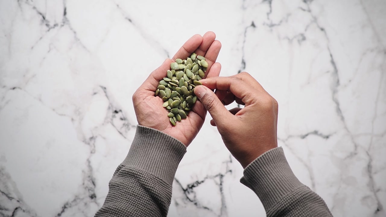 Top View of Hand Holding and Picking Green Pumpkin Seeds