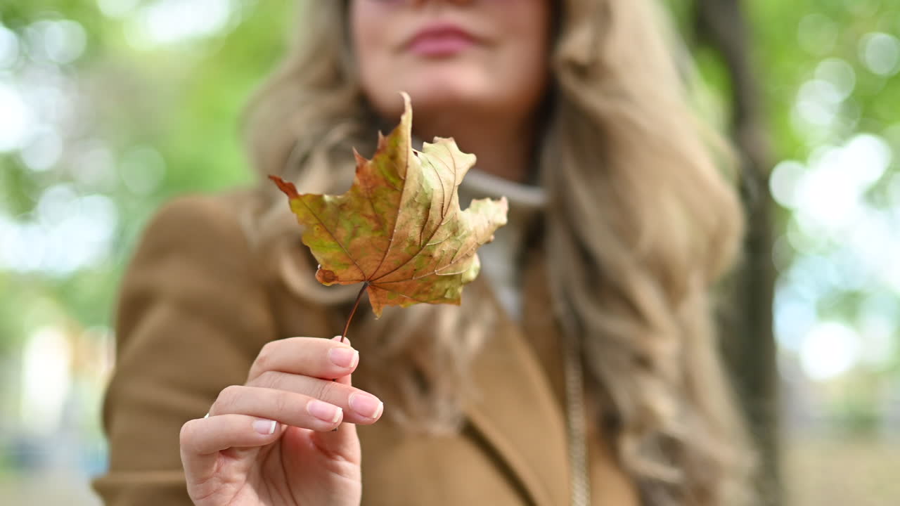 Brunette woman playing with a dried up leaf in a park