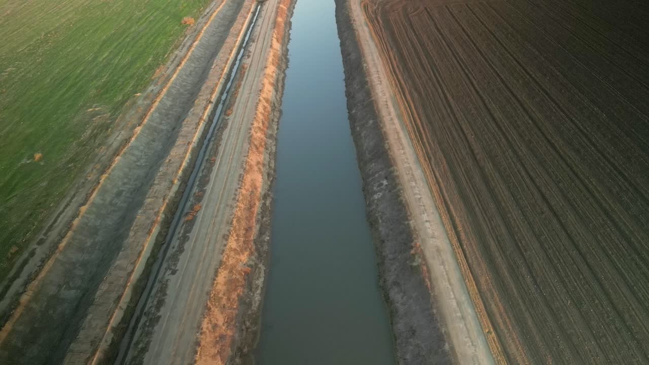 Overhead drone footage highlights the surroundings of Lake Tulare, featuring a mix of open fields and shimmering water channels reflecting the serene skies above.