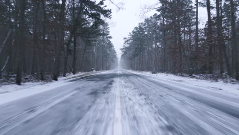 scenic road amidst a snowy forest on a winter day - moving shot