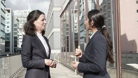 Mujeres-Empresarias-Dándose-La-Mano-Y-Hablando-En-La-Calle