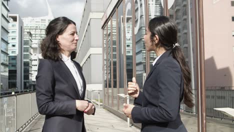 mujeres de negocios dándose la mano y hablando en la calle