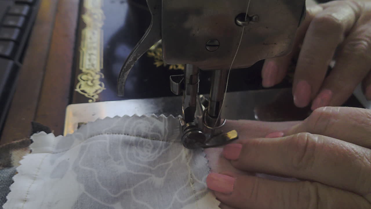 Close-up Tangan Menjahit Kain Patchwork Bunga pada Mesin Jahit Antik Berusia 100 Tahun. Menampilkan Detail Mekanis Tajam dan Estetika Gaya Hidup Nostalgia 2026