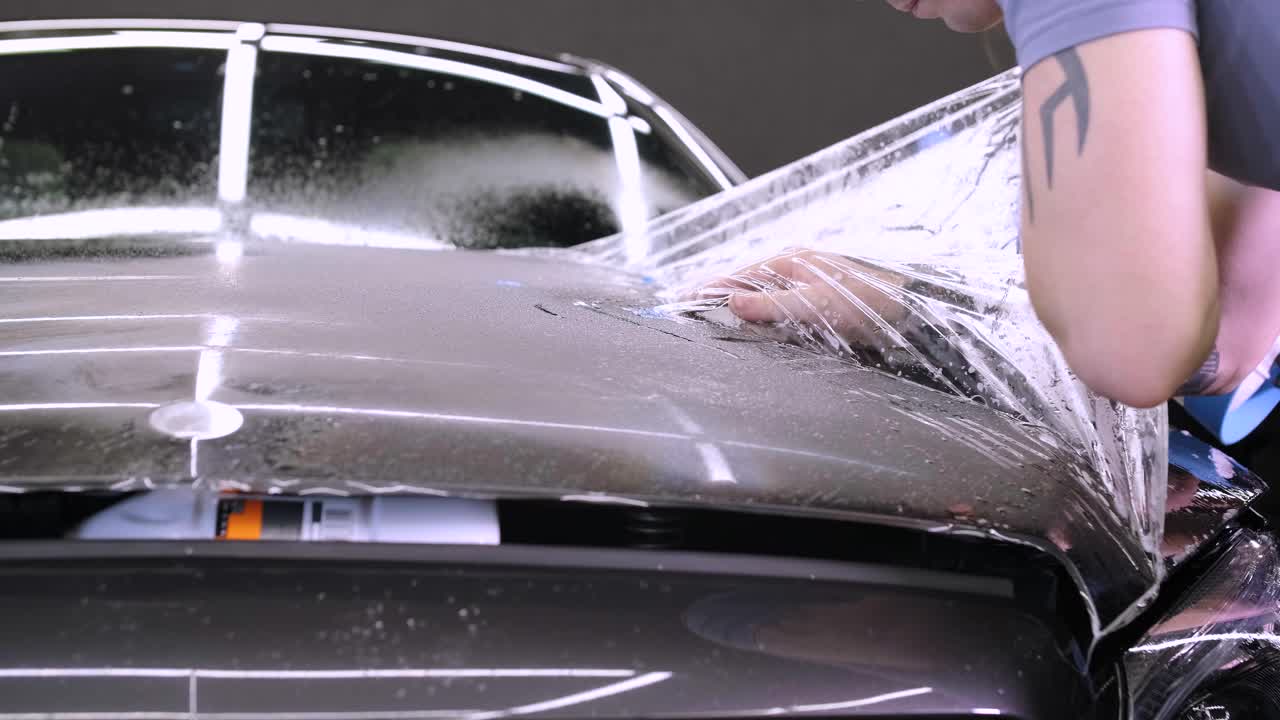 Man covering car with vinyl polyurethane tape. Films for the car. Sticker protective film on the car