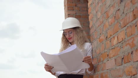 female architect in business attire standing outdoors at construction site. the architect reads the architectural plan