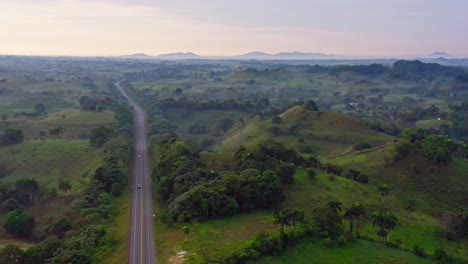 Samana-Highway-cutting-through-stunning-green-landscape,-Dominican-Republic,-drone